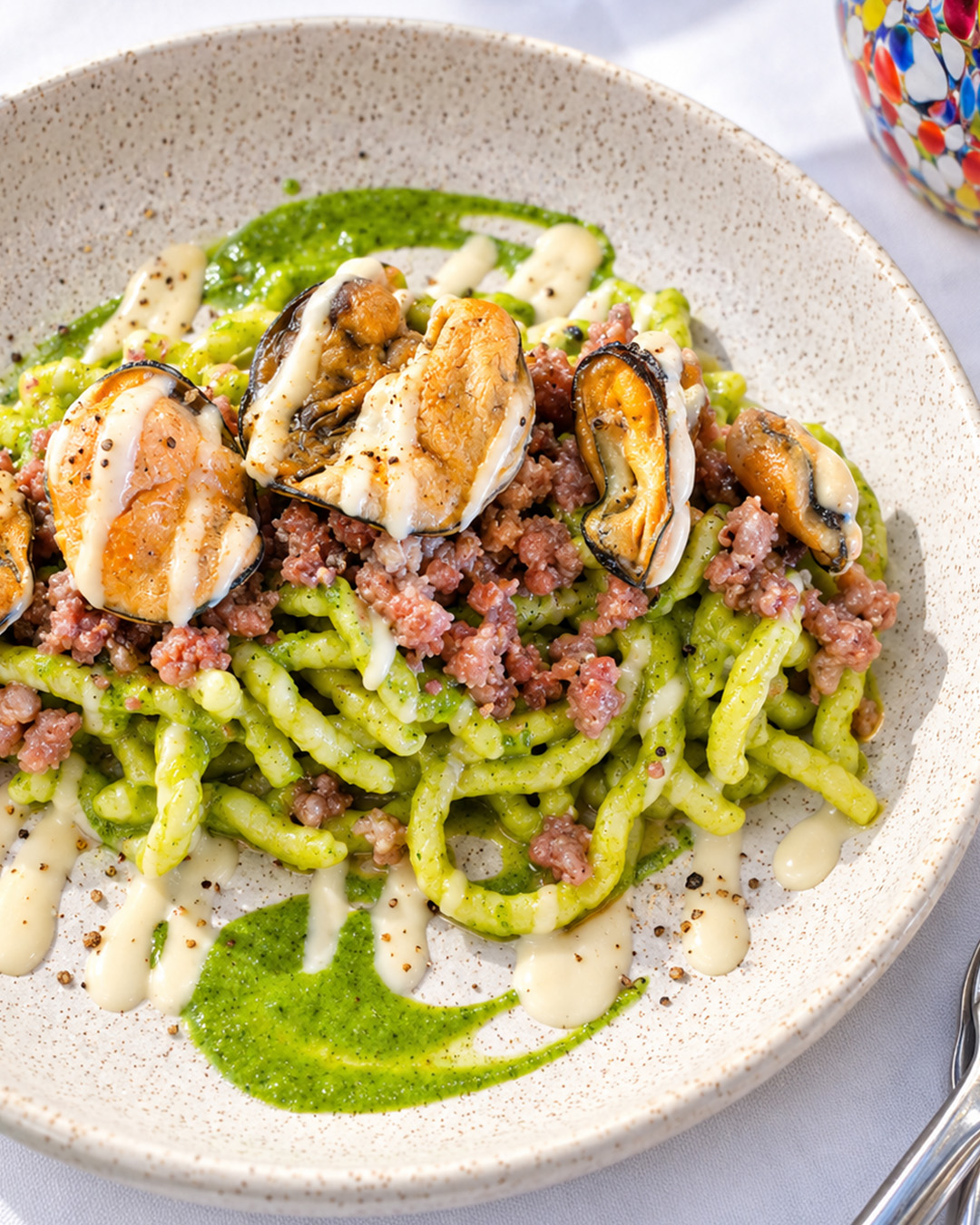 Spaghettoni maison dressés avec sauce verte et moules
